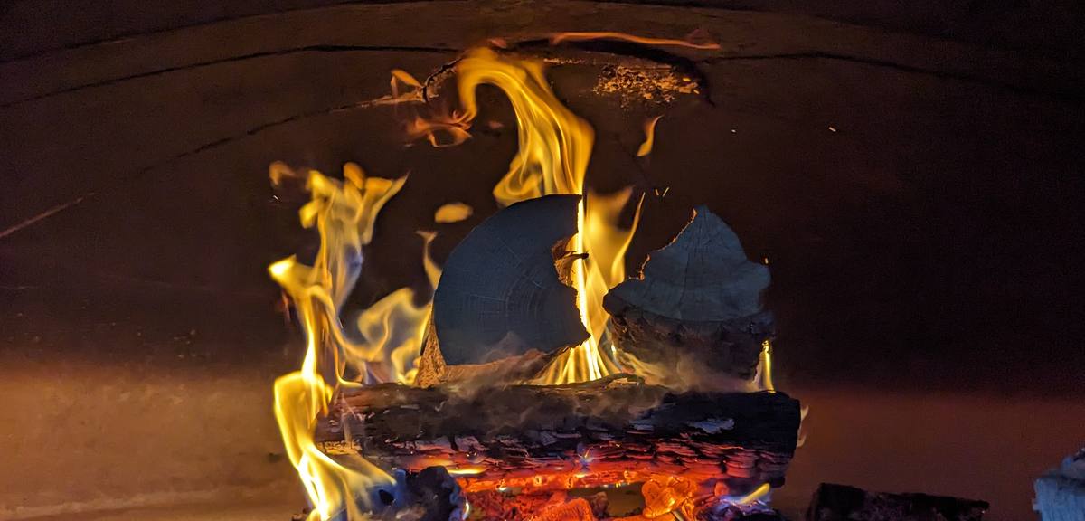 A log burning on the floor of the wood-fired oven