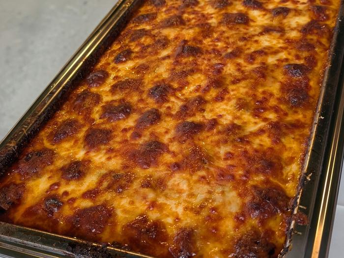 A close look at the meatball dish, two-inch meatballs in red sauce under a layer of mozzarella and provolone browned in the wood-fired oven