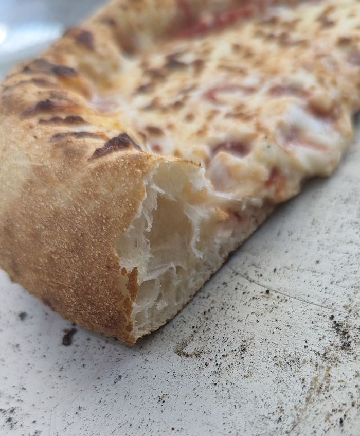 A torn crust showing the open, airy crumb inside