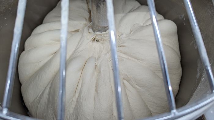 The same dough later in the mix, smooth and climbing the hook