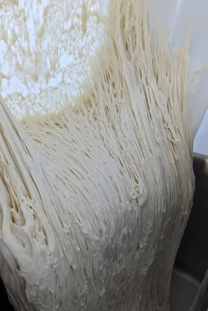The same poolish being poured into the mixer, stringy and slack